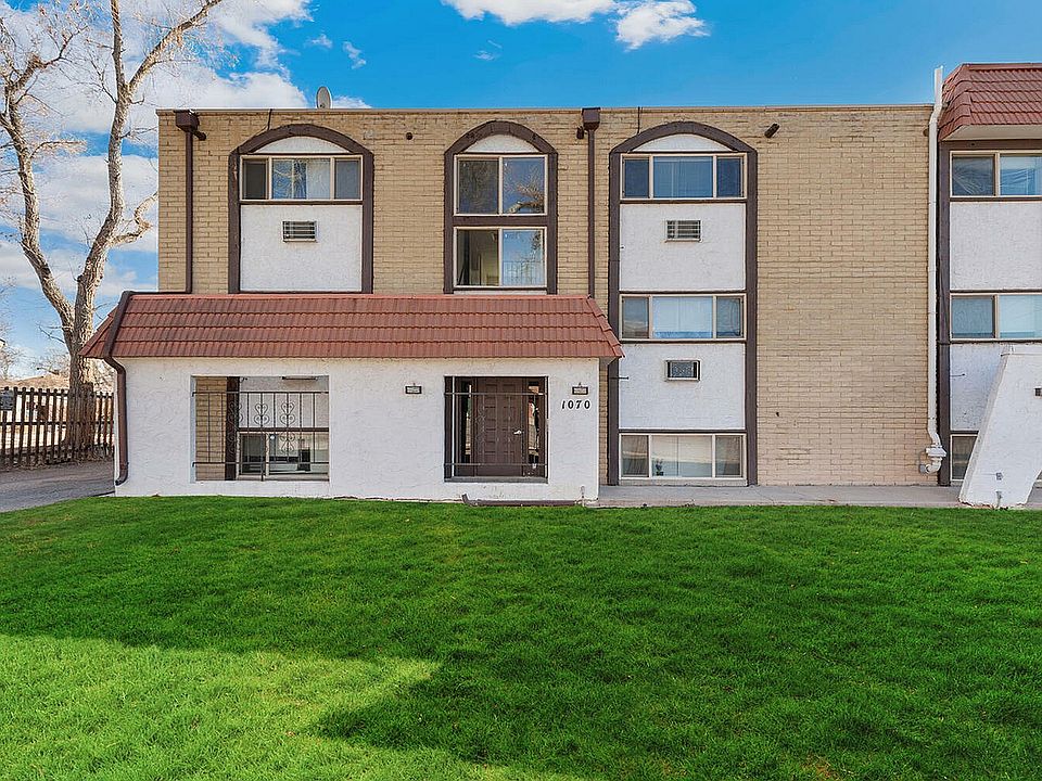Charming apartment exterior with modern architecture, featuring red-tiled roof and lush green lawn.