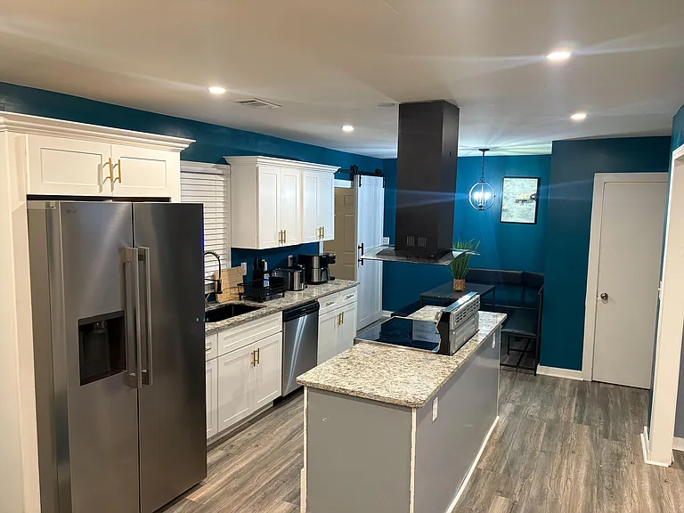 Updated kitchen with stainless appliances, ample cabinetry, and a large island with range and vent hood.