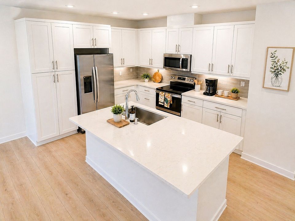 Gourmet kitchen with sleek white cabinetry, Calacatta quartz countertops, stainless steel appliances, and a large center island.