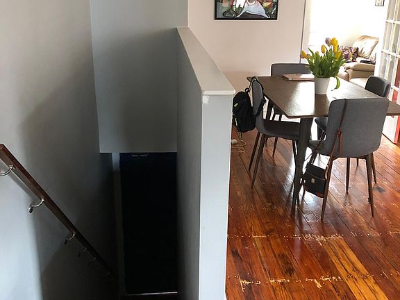 Shows knee wall at the top of the steps entering the apartment, with the eat-in kitchen's dining area.