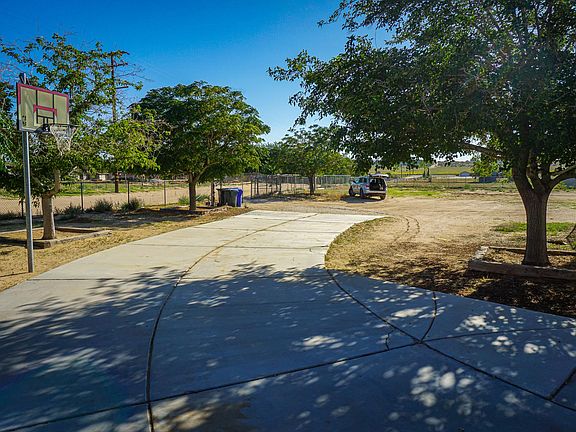 Fenced yard with entry drive gate and driveway with basketball hoop.