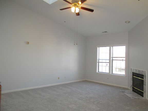 Bright and spacious living room with plush carpet, vaulted c