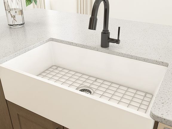 White apron front sink within the kitchen featuring matte black faucets