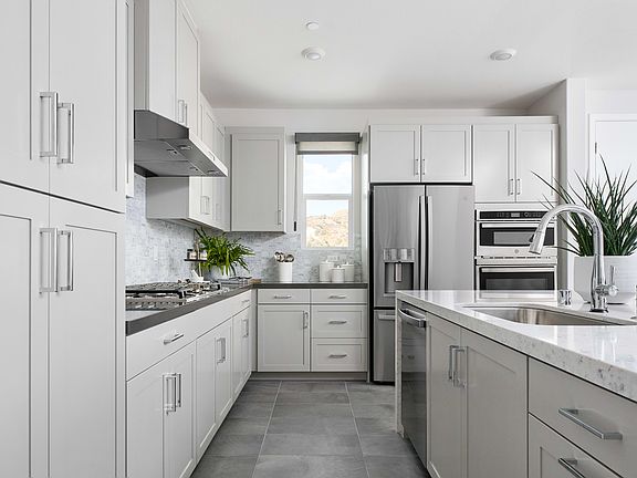 A modern, well-equipped kitchen with white cabinets, stainless steel appliances, and a central islan