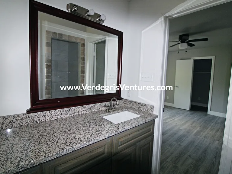 Principal bathroom: This private bathroom includes a stall shower, granite counters, and a porcelain sink, illuminated by warm west_facing natural light