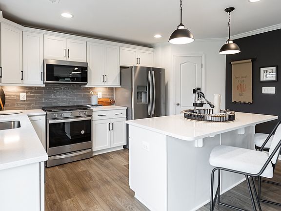 Island kitchen with white cabinets in a DRB Homes Carnegie II model in the Chesterfield community.