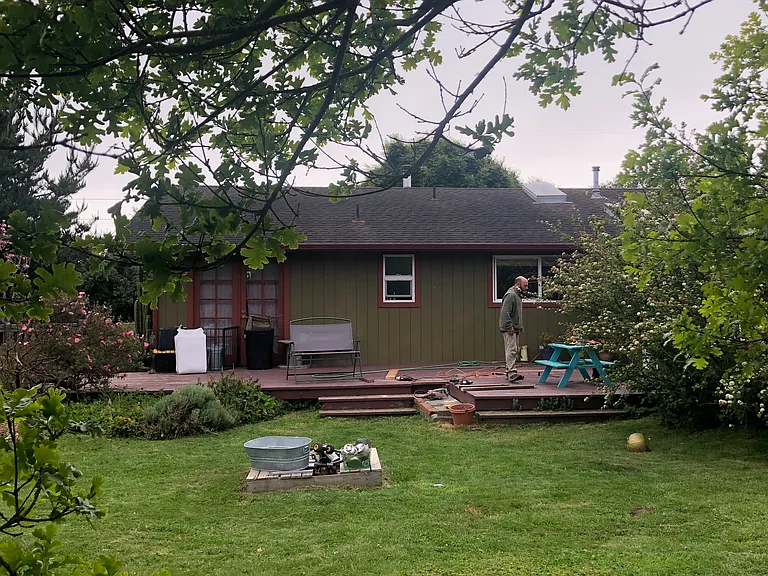 This image shows part of the backyard looking back towards the house. the French door on the left leads to the smallest bedroom.