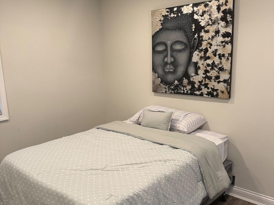 Neatly furnished bedroom with a comfortable bed, ceiling fan, and wood-look flooring for easy upkeep.
