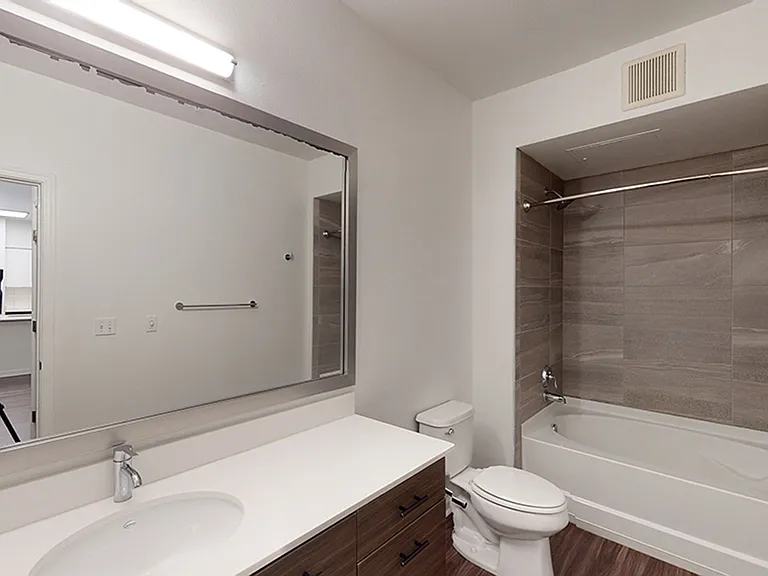 Apartment bathroom with large soaking tub and wood-style flooring.