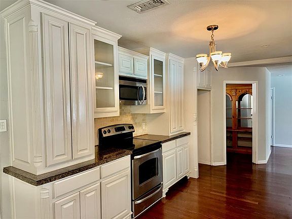Updated Kitchen featuring, an inviting chandelier, stainless steel appliances, dark easy care wood flooring, and white cabinetry. Leads into the large storage Pantry.