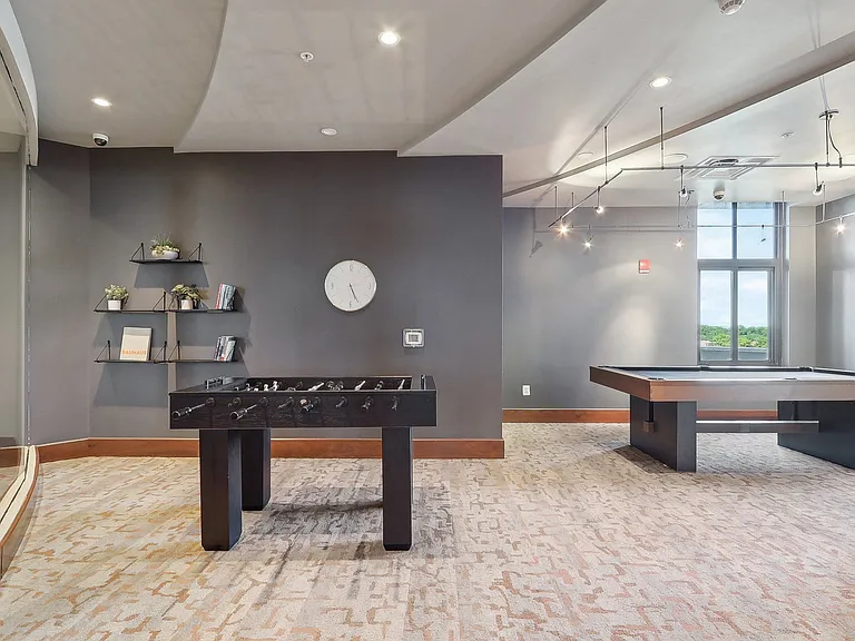 A clubroom with pool table and shuffleboard table and a window