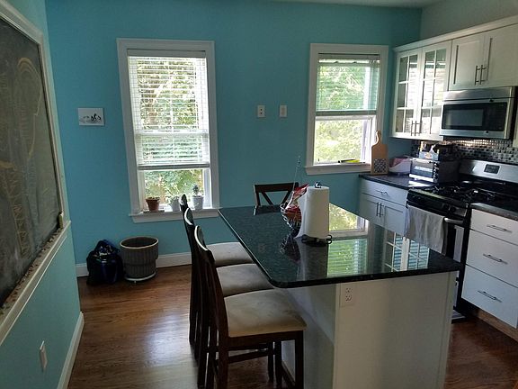 kitchen with lots of light, chalkboard wall, stainless steel appliances, granite counter tops, gas stove, and a large pantry for food storage