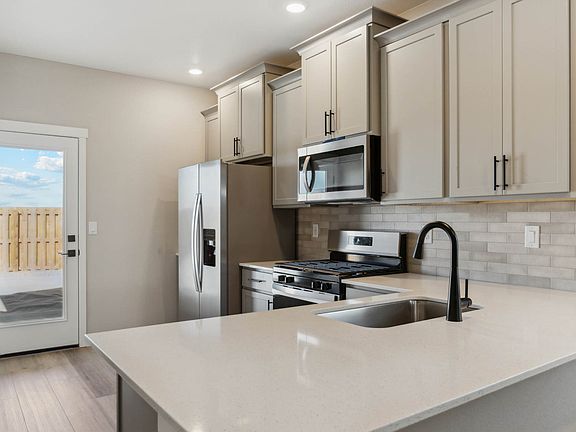 The kitchen has a stainless steel appliances and plank flooring.