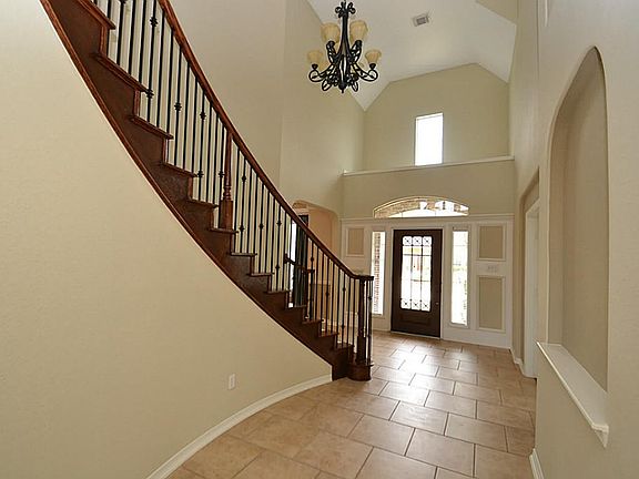 Entry offering a glass front door with wrought iron accents, tile floors, two story high ceilings and access to a half bath.