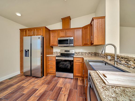 Kitchen - Solid wood cabinets, upgraded nickel hardware, title back splashes, highly upgraded stainless appliance package, center island, and country farm sink with pull-out faucet, recessed lighting.