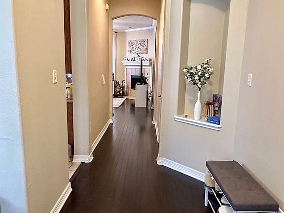 Corridor featuring dark wood-style flooring, ornamental molding, and arched walkways