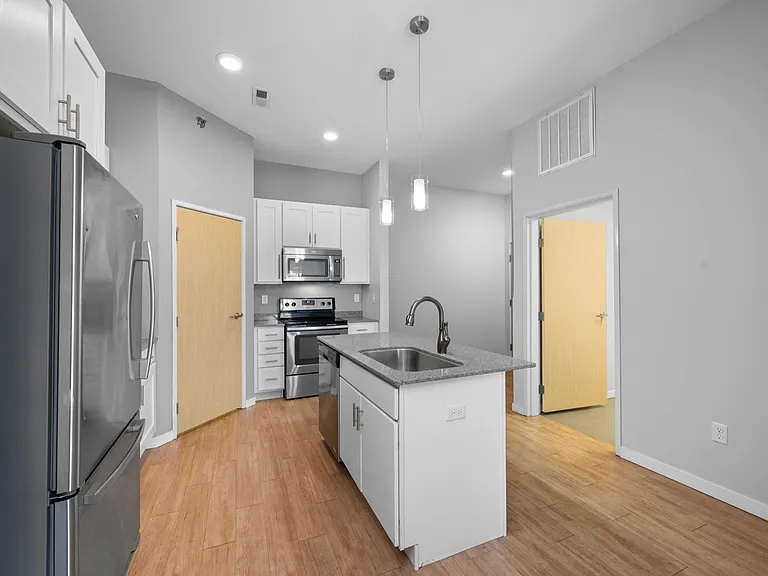 Modern kitchen with stainless steel appliances, sleek cabinetry, and a central island under pendant lighting. Modern kitchen with stainless steel appliances, sleek cabinetry, and a central island under pendant lighting.