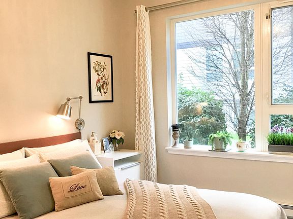 Good size bedroom with south facing window, queen bed and identical bedside tables, hardwood floor, and 9-foot high ceiling.