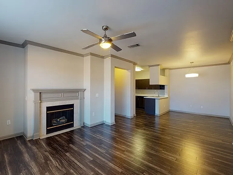 Apartment living room with wood-style flooring and fireplace in select homes.