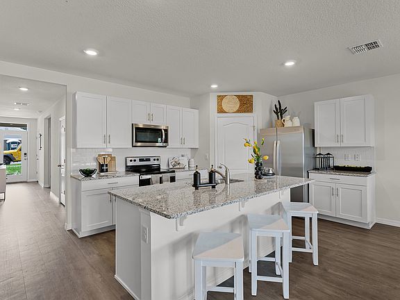 Modern kitchen with island seating, granite countertops, and stainless steel appliances.