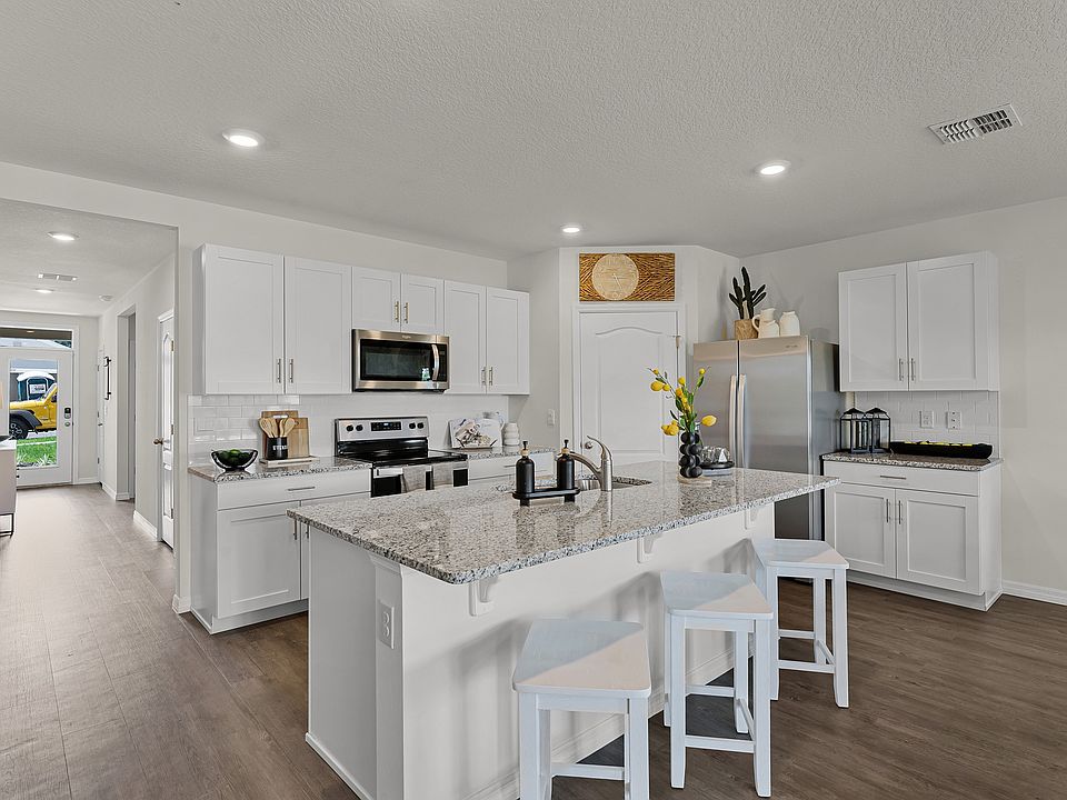 Modern kitchen with island seating, granite countertops, and stainless steel appliances.