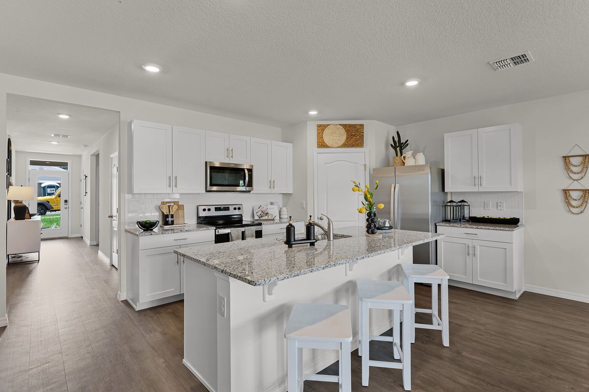 Modern kitchen with island seating, granite countertops, and stainless steel appliances.