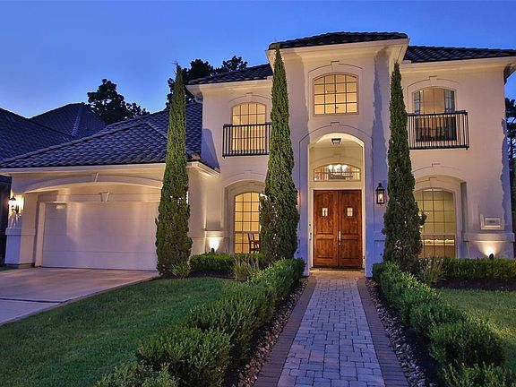 CUSTOM STUCCO HOME WITH TILE ROOF AND DECORATIVE IRON BALCONIES - The home glows at night with striking up-lights, custom walk way with brick pavers and custom landscaping.