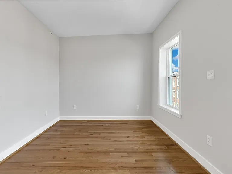 The larger bedroom has two large windows and a storage closet.