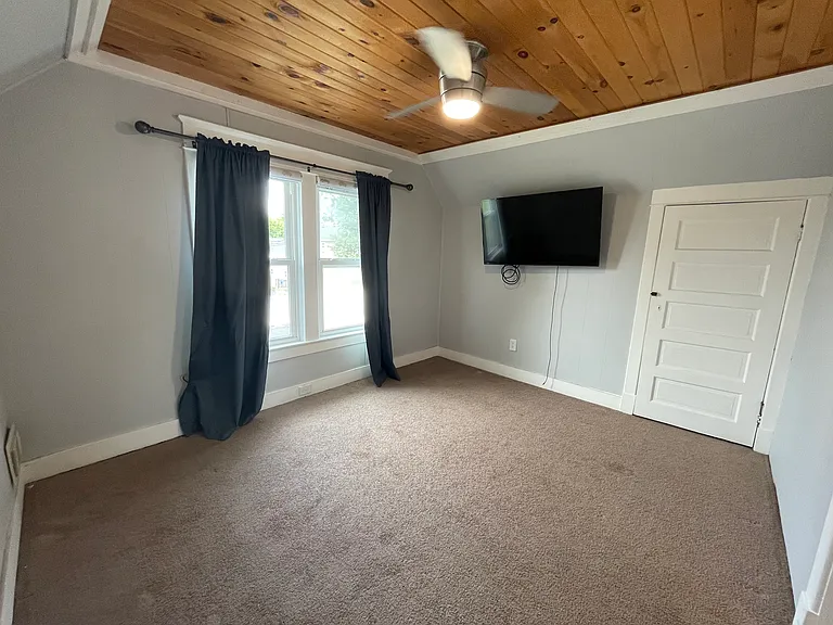 Spacious second-floor bedroom featuring two closets, a ceiling fan, natural light, and a warm wood ceiling that adds character to the room.