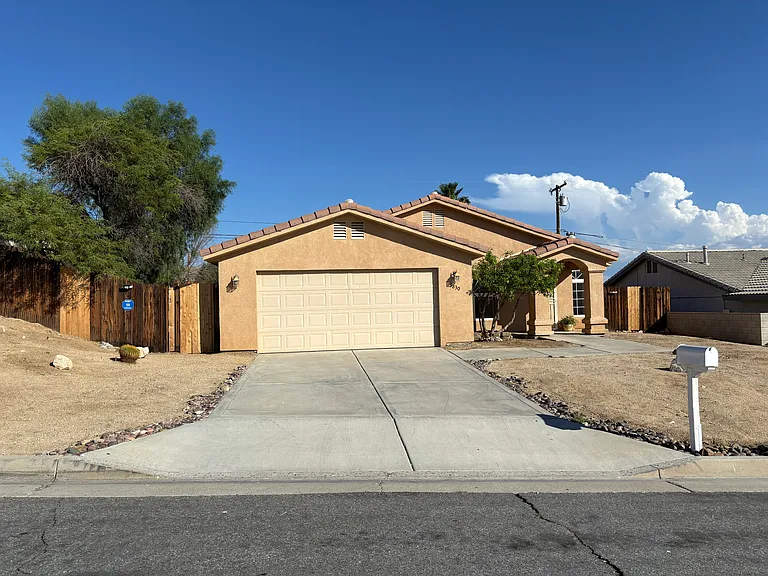 Front exterior with attached 2-car garage, wide driveway, and low-maintenance desert landscaping.