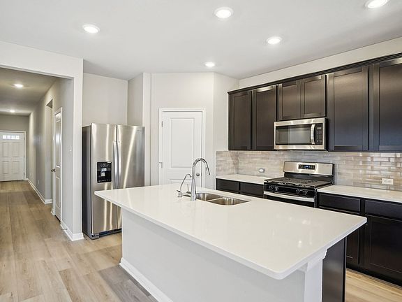 The kitchen features espresso-colored cabinets and quartz countertops.