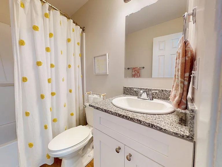 Charming bathroom featuring a granite countertop, modern sink, and a delightful shower curtain with yellow accents. Charming bathroom featuring a granite countertop, modern sink, and a delightful shower curtain with yellow accents.