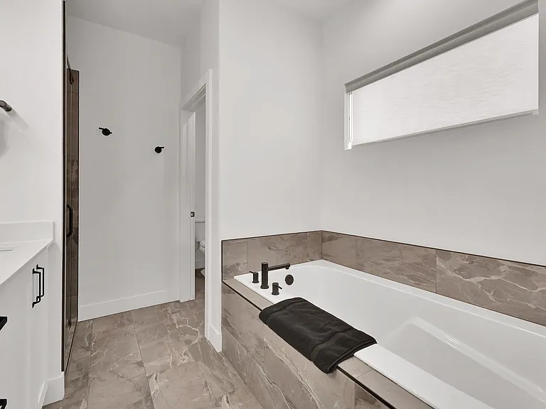 Master bathroom with his and hers sinks, walk in shower, large bathtub, and separate toilet room