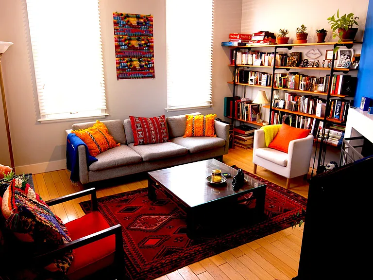 Living room with large built-in bookshelf wall and fireplace. Windows have white blinds. House will be rented unfurnished.