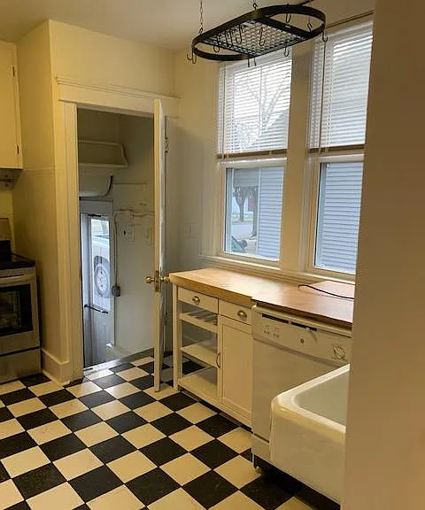 Kitchen has original farmhouse sink, modern black and white porcelain tile.