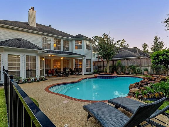 Beautiful backyard with wrought iron fence around the pool area. Notice the covered patio!