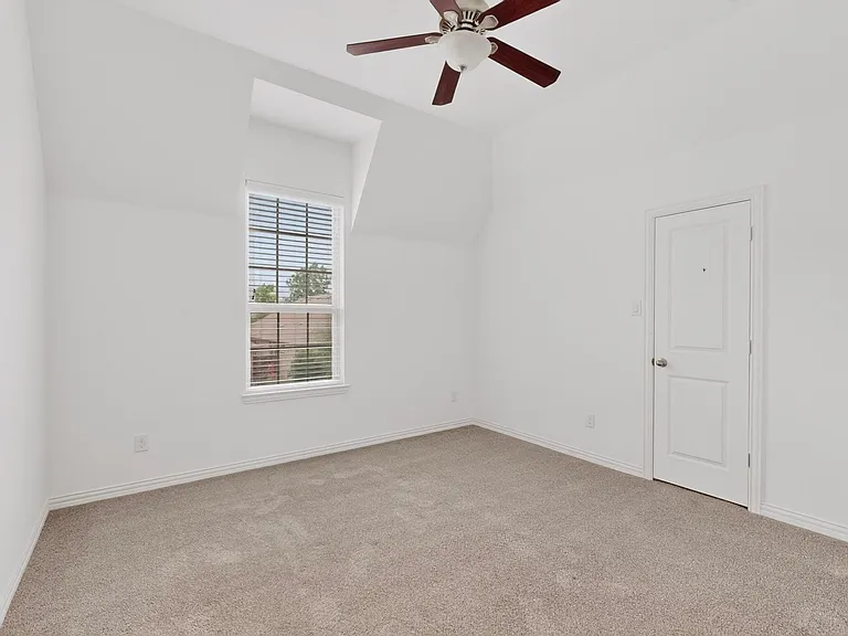 A bright bedroom featuring a ceiling fan and a window