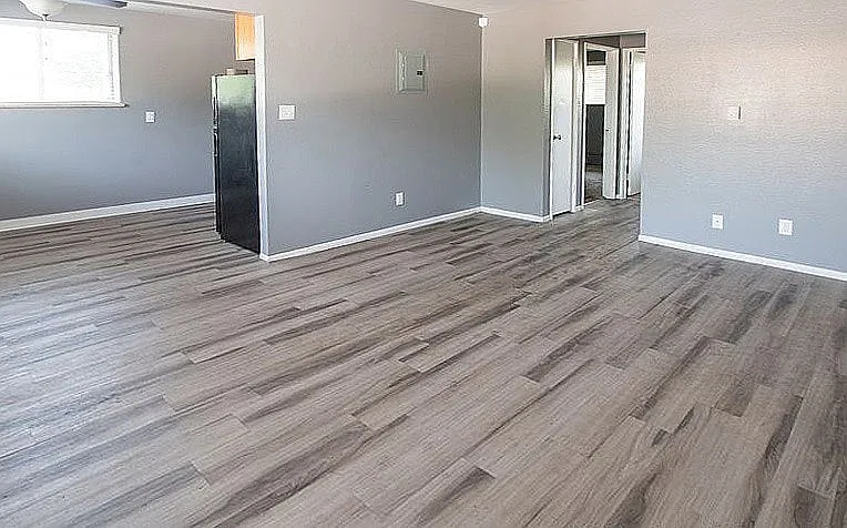 Modern apartment interior with sleek laminate flooring, featuring an open layout with ample natural light and neutral-toned walls.