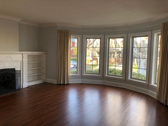 Living Room with wood-burning fireplace, built-in bookcases and bay windows.
