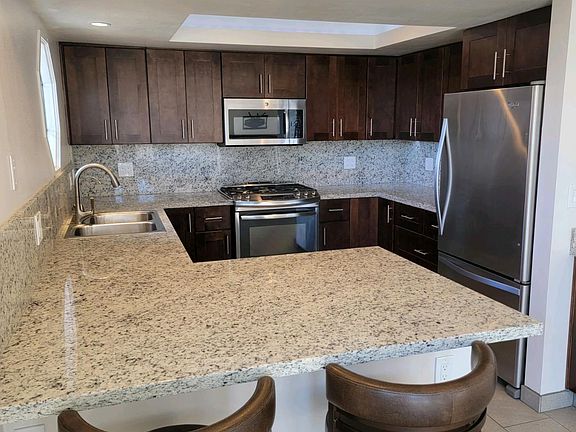 Kitchen with eating bar and space for a dining table and chairs. Refrigerator included in rental. Under cabinet lighting. Reverse osmosis water system.