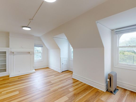 Sunlit room with a large window and wood-like flooring