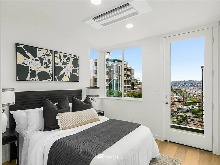Primary bed room with a mini split, closet, attached bathroom, and balcony with view of the Space Needle.