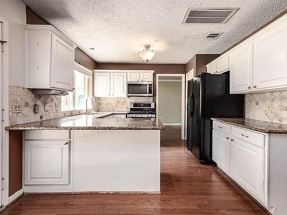This spacious kitchen features large windows, white cabinets, granite countertops, and modern tile backsplash!