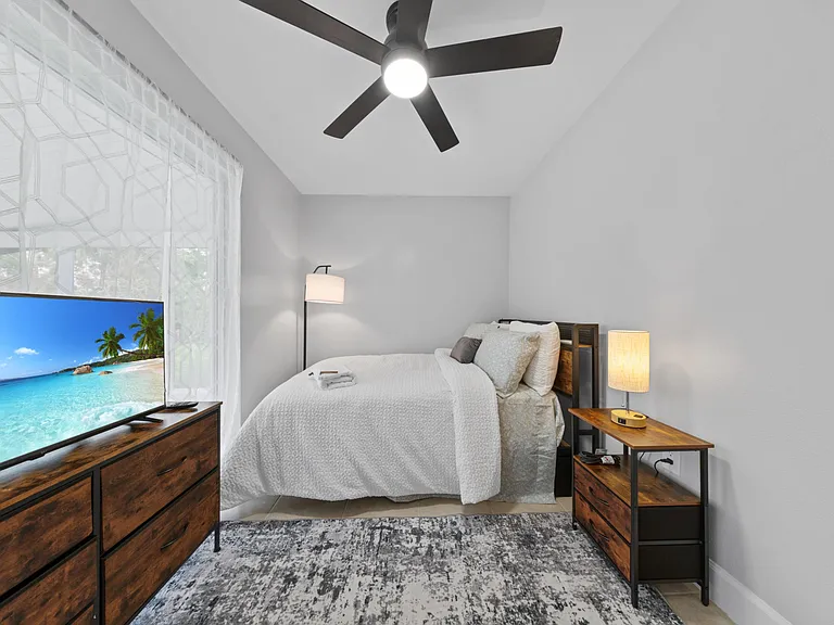 Nightstand with reading lamp, mini fridge in the room, TV comfort without the clutter.