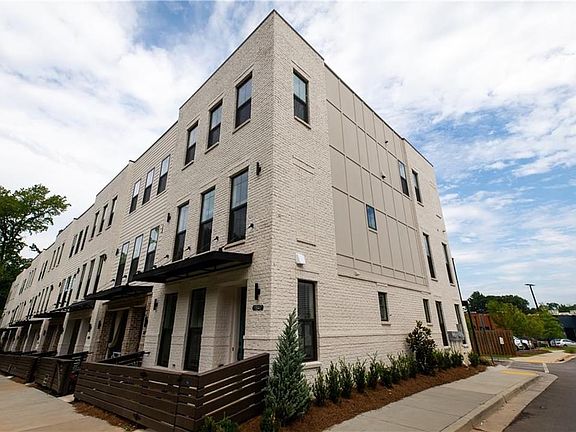 STATELY END UNIT OF WHITE-PAINTED BRICK, FENCED GATE ENTRY, AND BEAUTIFUL LARGE WINDOWS PROVIDING LI