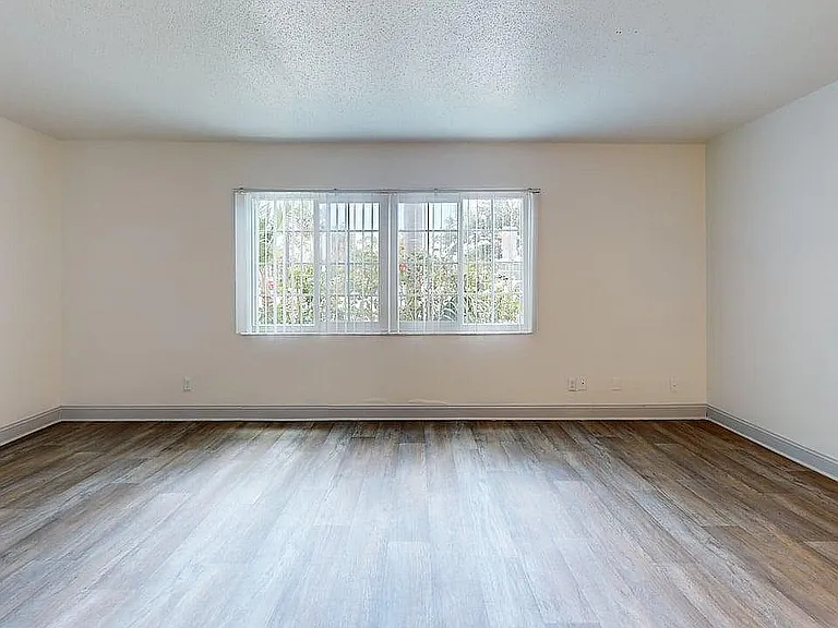 Bright and spacious living room with large windows and elegant wood-look flooring, perfect for creating a warm and inviting atmosphere.