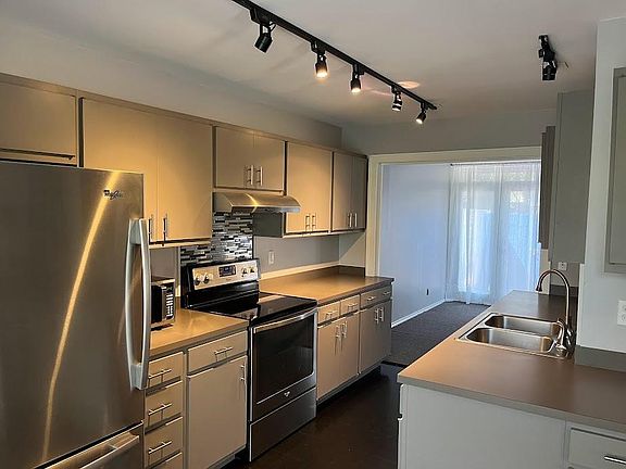 Kitchen view into living room; north facing French doors, left of fireplace with sheer curtains.