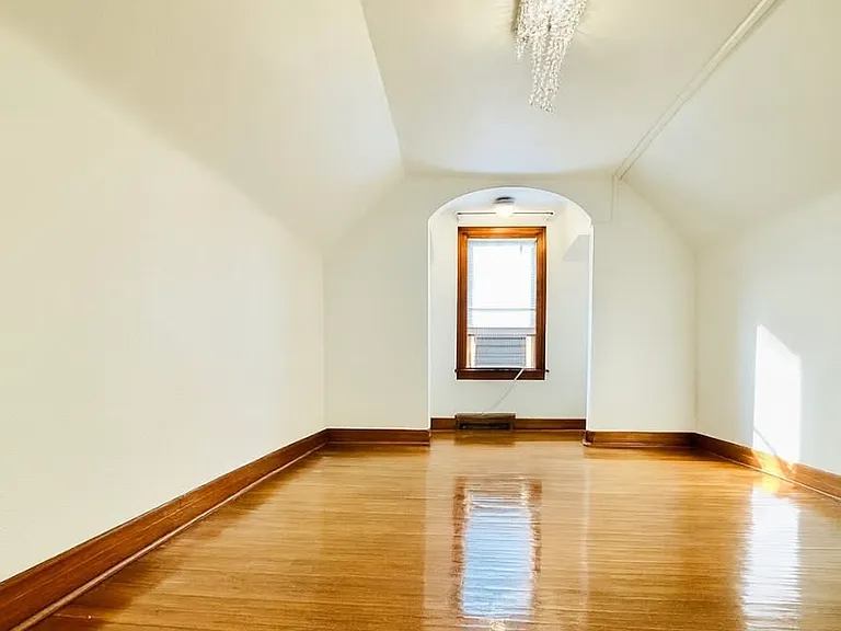A spacious bedroom with a large glass window overlooking the garage and backyard. It offers a private, quiet atmosphere_ideal for studying, relaxing, or enjoying a peaceful moment of calm.