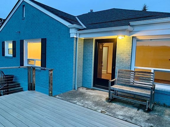 Front door with porch & large deck overlooking city.