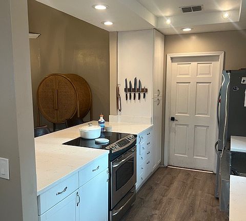 Bright kitchen with white cabinets, plenty of prep space, and open flow to dining and patio.